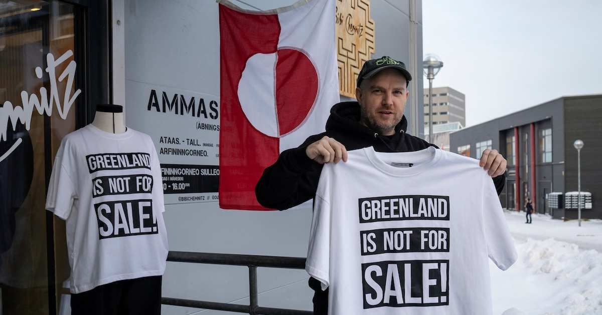 ​A shop owner David Rogilds holds a shirt that he sells in Nuuk, Greenland, January 14, 2026. 