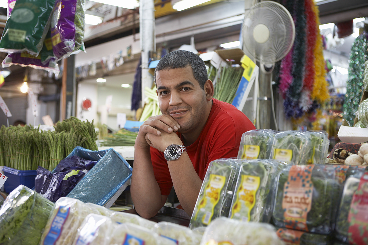 A small business owner in his store surrounded by produce