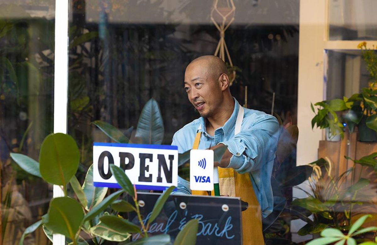 A small business owner puts an Open sign in his store window. The key for small business growth? More digital support.