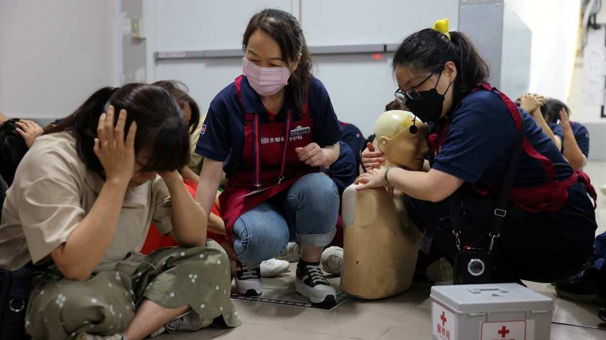A staff member holds a dummy as staff and customers take shelter at a storage room, during an air raid exercise at a PX Mart supermarket as part of the civil defence drills in Taipei, Taiwan