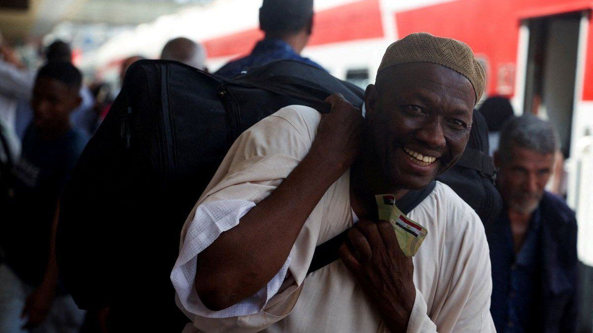 ​A Sudanese man smiles while carrying his luggage, as families displaced by conflict between the Sudanese Armed Forces and the Rapid Support Forces (RSF) crowd at Cairo's main station to board a free train with a voluntary return coordinated by the Egyptian government to Aswan, where buses will take them back to their homes in Khartoum, in Cairo, Egypt July 28, 2025.