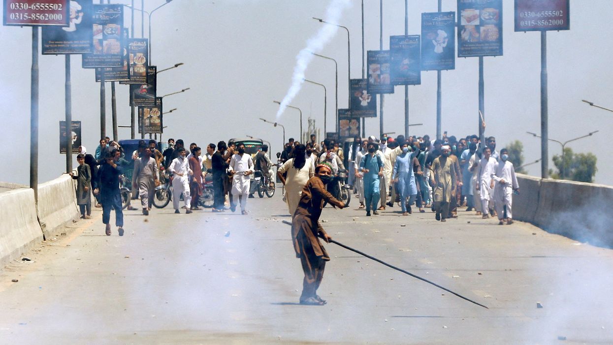 A supporter of Pakistan's former PM Imran Khan throws stones towards police during a protest against Khan's arrest in Peshawar.