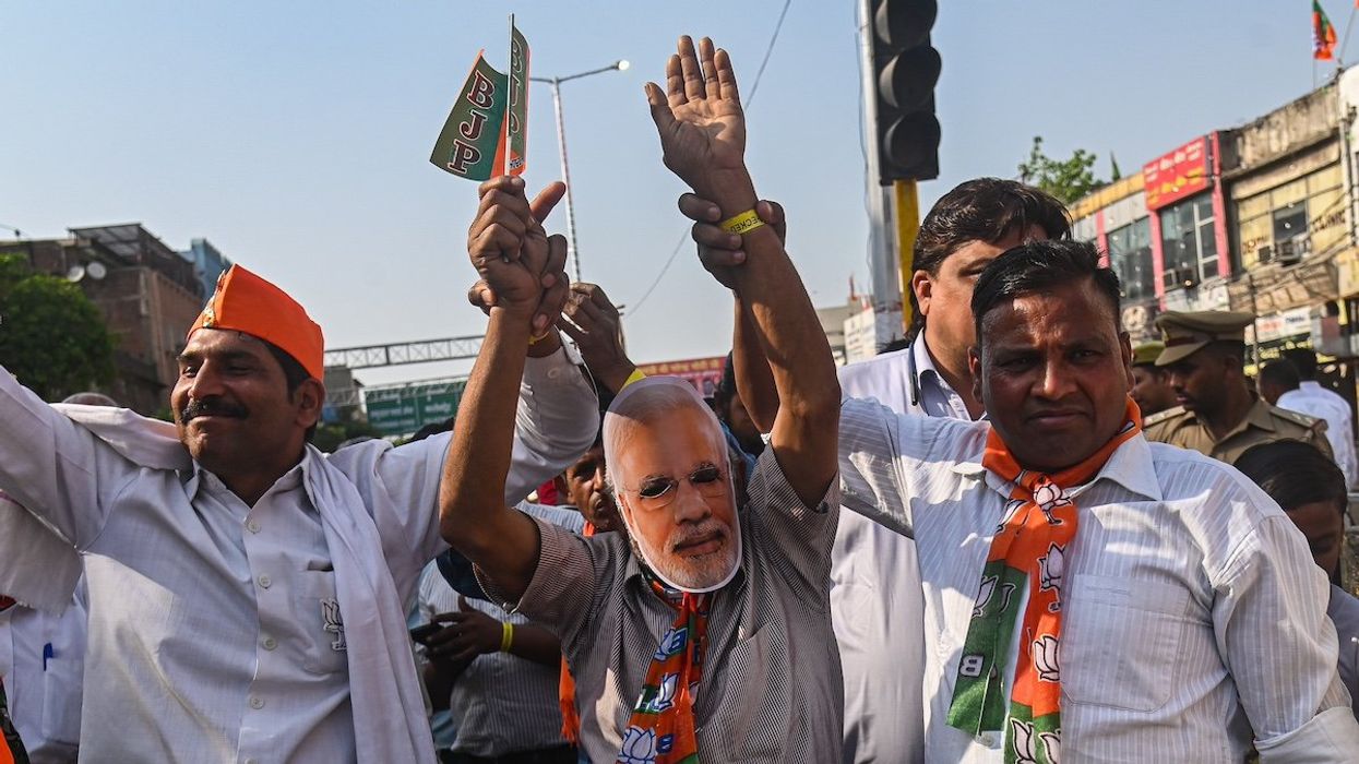 A supporter of the Bharatiya Janata Party (BJP) is wearing a face mask of Indian Prime Minister Narendra Modi and dancing during a roadshow ahead of the Indian General Elections in Ghaziabad, Uttar Pradesh, India, on April 6, 2024.