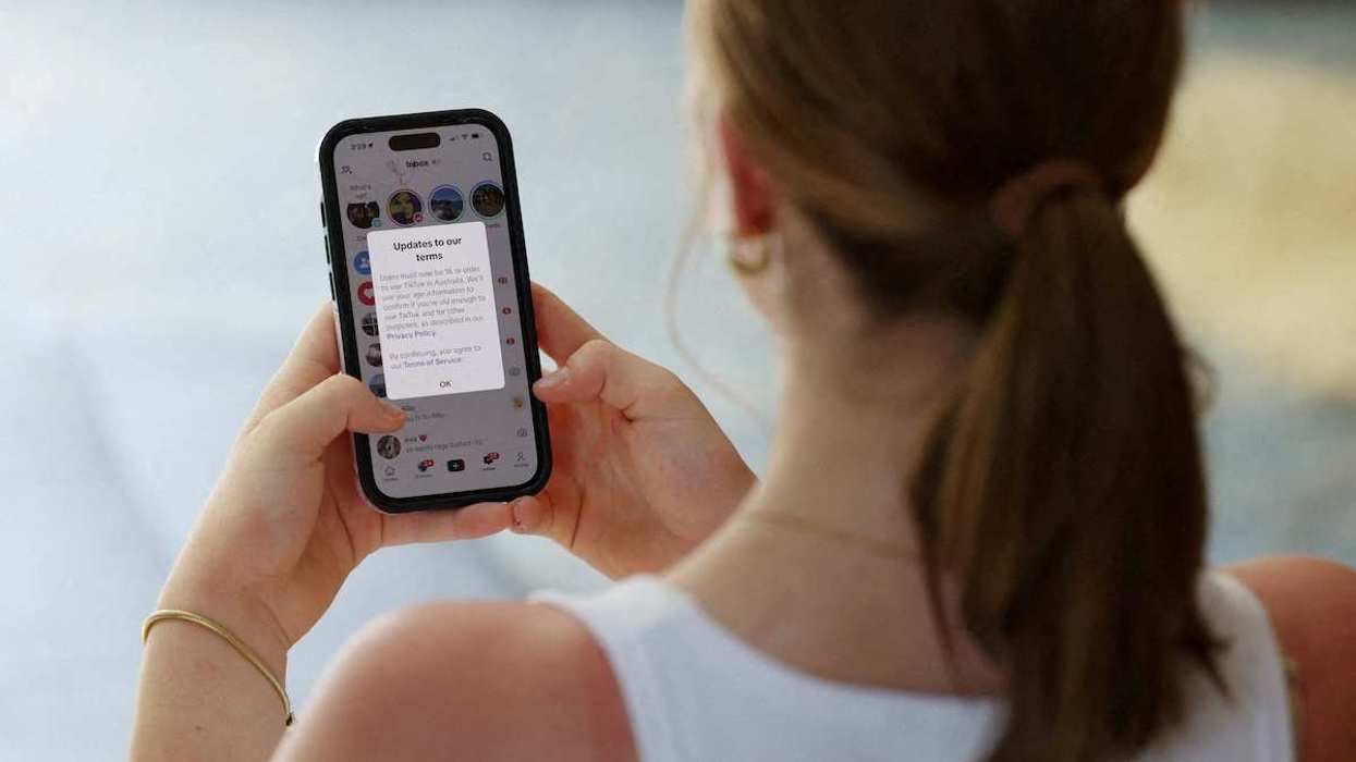 A teenager poses holding a mobile phone as a law banning social media for users under 16 in Australia takes effect, in Sydney, Australia, on December 10, 2025.