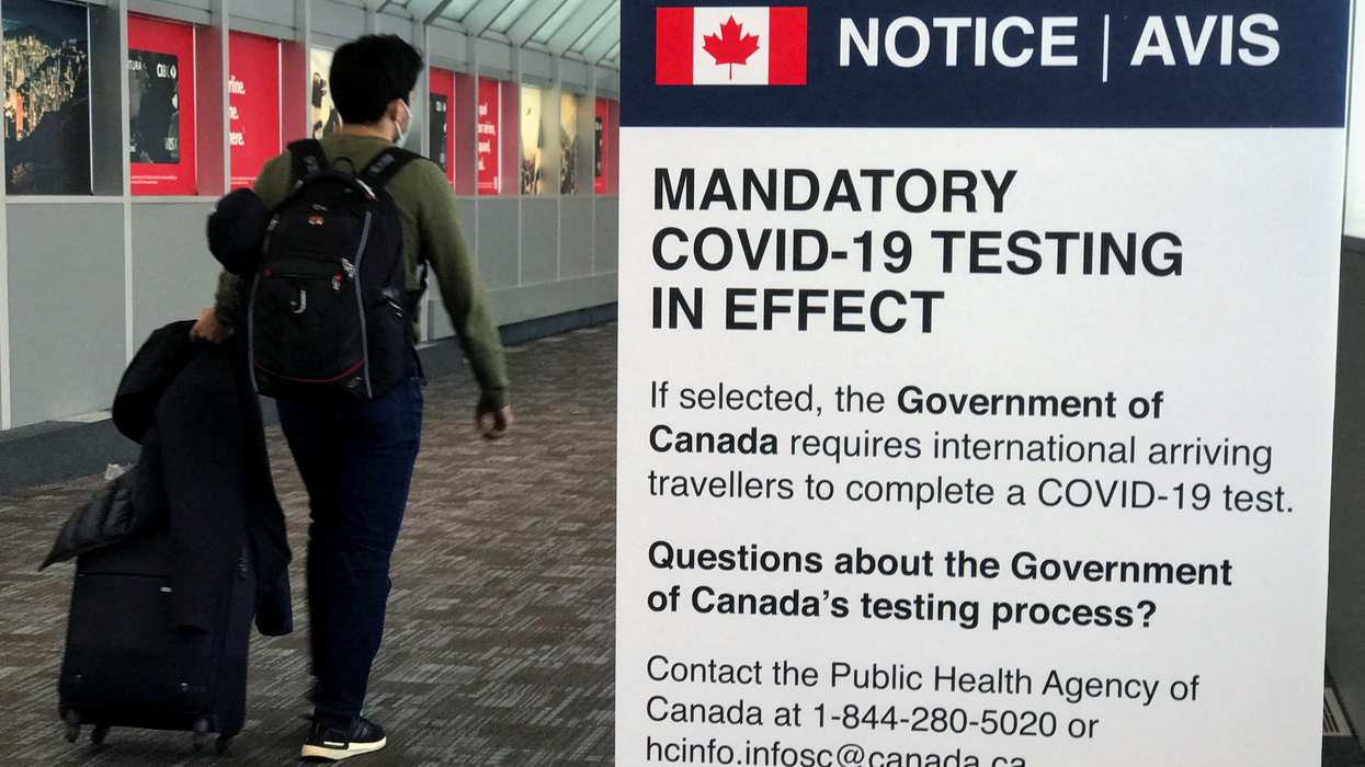 A traveler walks past a "Mandatory COVID Testing" sign at Pearson International Airport in Toronto.