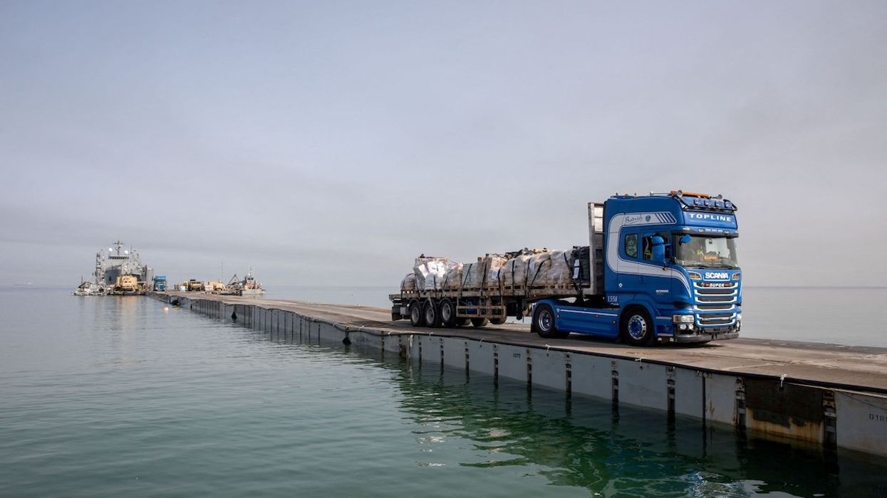 A truck carries humanitarian aid across a temporary pier to deliver aid off the Gaza Strip.
