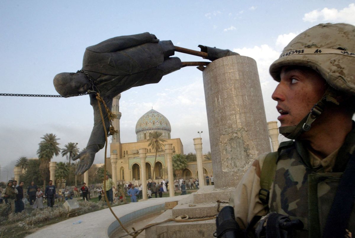 A U.S. soldier watches as a statue of Iraq's President Saddam Hussein fall in central Baghdad, Iraq, in April 2003. 