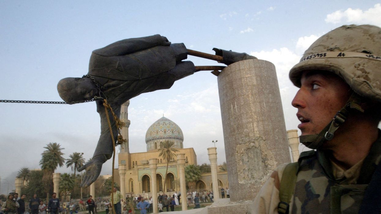 A U.S. soldier watches as a statue of Iraq's President Saddam Hussein fall in central Baghdad, Iraq, in April 2003.