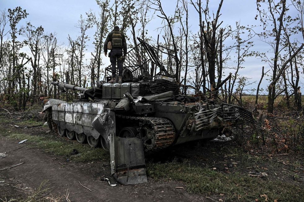 A Ukrainian soldier stands atop an abandoned Russian tank outside of Izyum, Kharkiv Region.