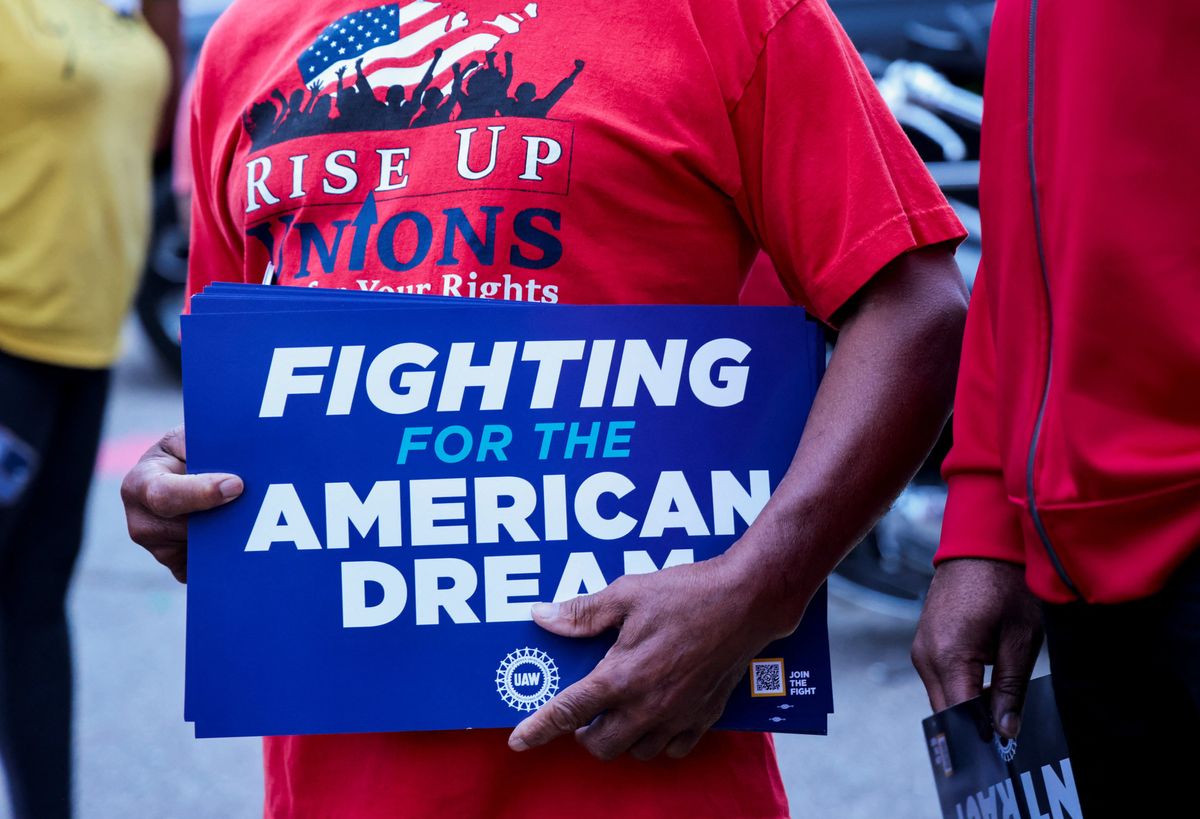 ​A United Auto Workers union member holds a sign outside Stellantis Sterling Heights Assembly Plant to mark the beginning of contract negotiations in Sterling Heights, Mich., in July. 