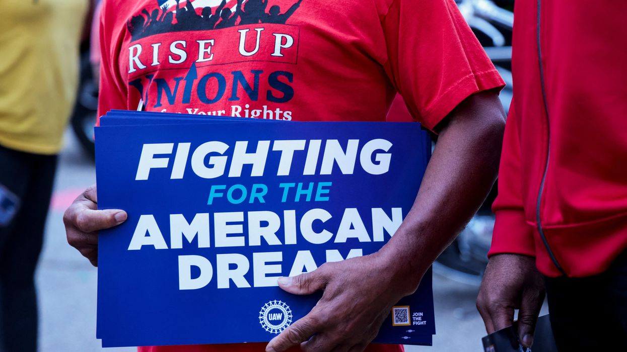 A United Auto Workers union member holds a sign outside Stellantis Sterling Heights Assembly Plant to mark the beginning of contract negotiations in Sterling Heights, Mich., in July.
