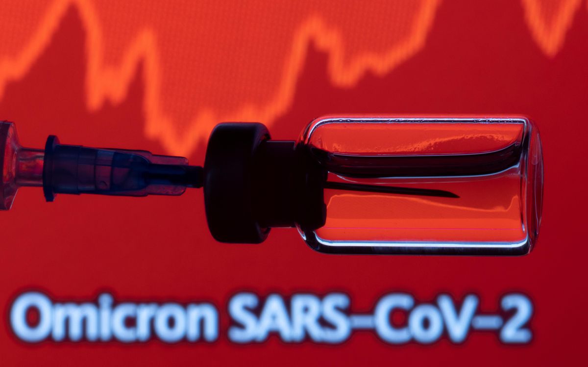 A vial and a syringe are seen in front of a displayed stock graph and words "Omicron SARS-CoV-2" in this illustration taken, November 27, 2021