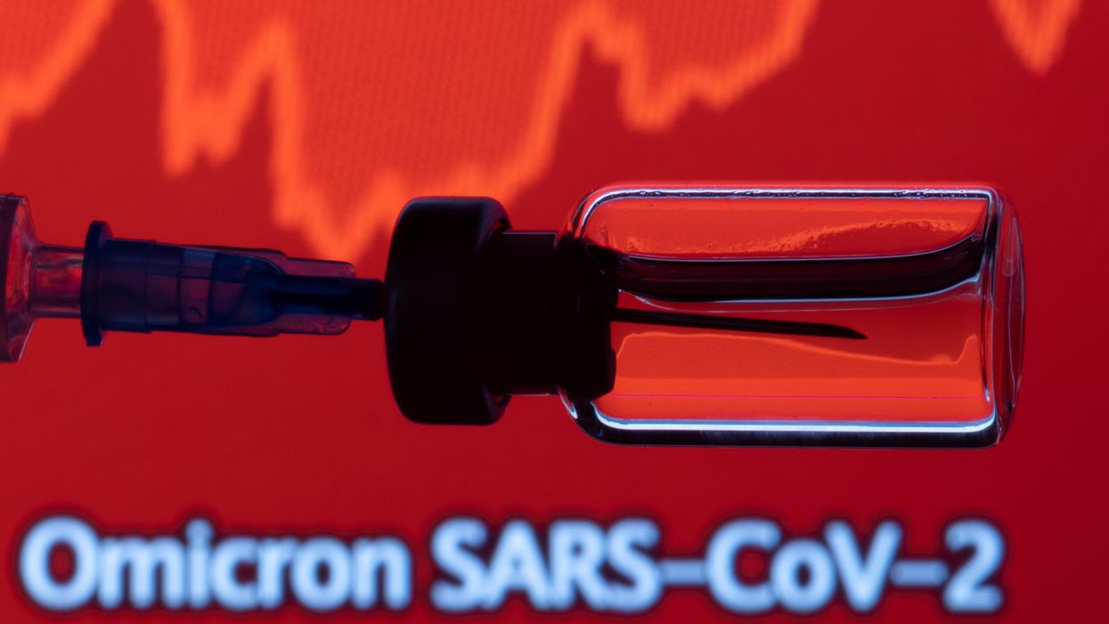A vial and a syringe are seen in front of a displayed stock graph and words "Omicron SARS-CoV-2" in this illustration taken, November 27, 2021