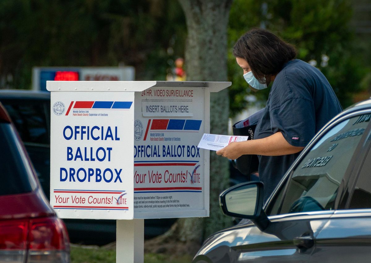 A voter drops off her vote by mail ballot at the Supervisor of Elections office on election day in West Palm Beach, Florida on August 18, 2020.