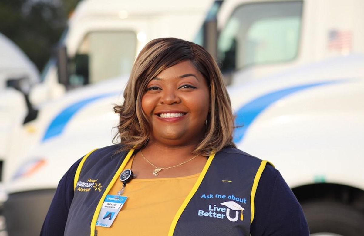 A Walmart employee with a big smile wearing an employee vest