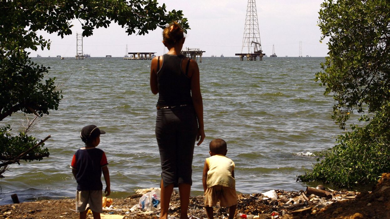 A woman and her sons stand on the edge of Maracaibo lake in front of oil rigs in Maracaibo February 15, 2008.