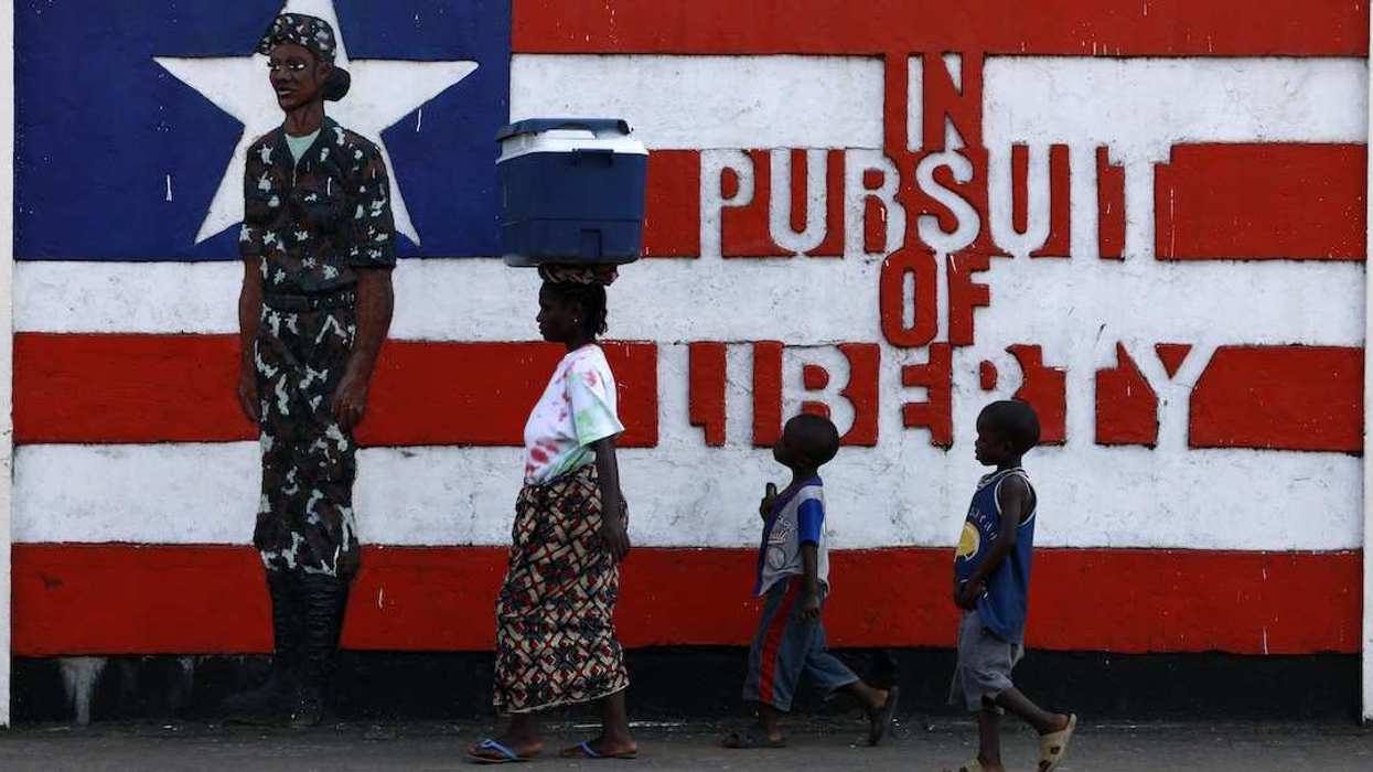 A woman and two children walk past a mural in Monrovia November 10, 2011.