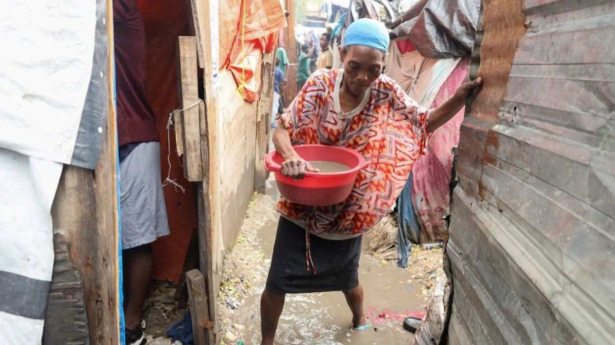 A woman carries water out of her home, after floods caused by the outer bands of Hurricane Melissa killed several people, in Port-au-Prince, Haiti, October 29, 2025.