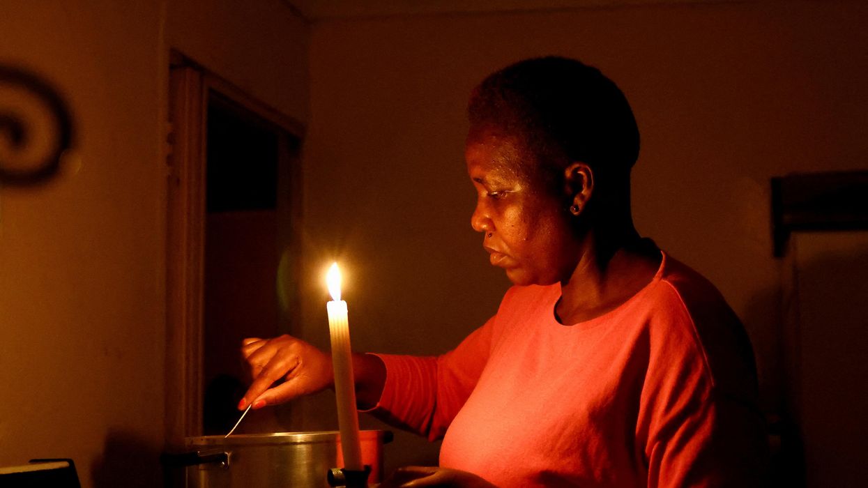 A woman cooks by a candlelight during one of the frequent power outages in South Africa.