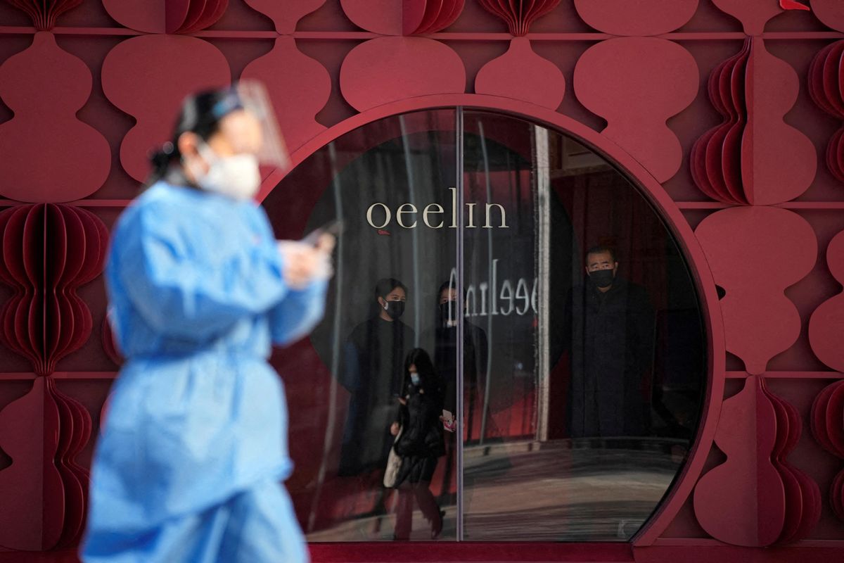 A woman in a protective suit walks past a shop as COVID outbreaks continue in Shanghai, China.