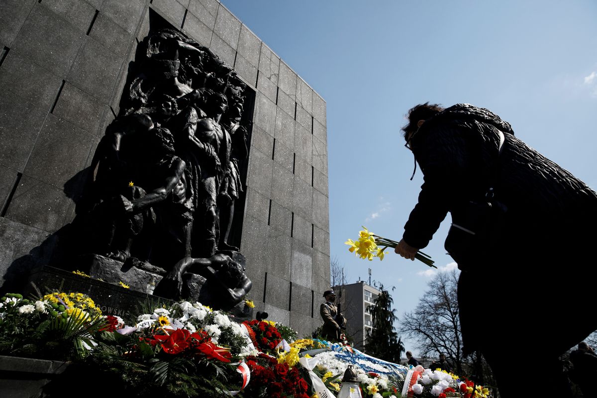 A woman lays daffodils during the commemoration of the 78th anniversary of the Warsaw Ghetto Uprising, in front of the Warsaw Ghetto monument in Warsaw, Poland.