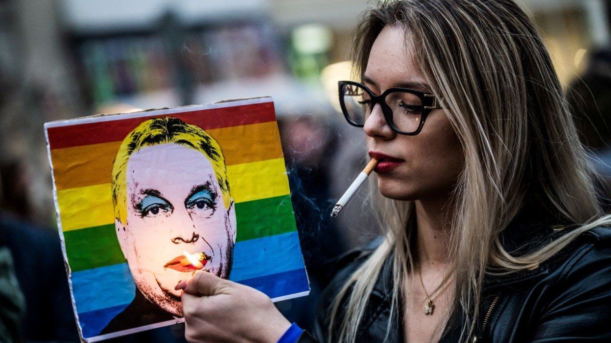 ​A woman lights a cigarette placed in a placard depicting Hungary's Prime Minister Viktor Orbán in Budapest, Hungary, on March 25, 2025.