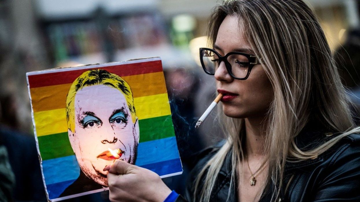 A woman lights a cigarette placed in a placard depicting Hungary's Prime Minister Viktor Orbán in Budapest, Hungary, on March 25, 2025.