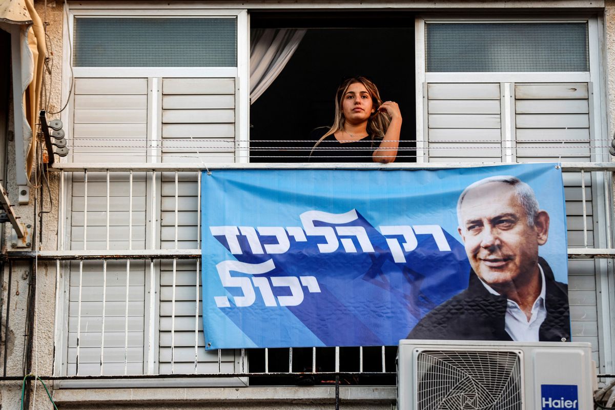 A woman looks out of a window displaying a campaign banner of Former Israeli Prime Minister Benjamin Netanyahu in Ramla, Israel.