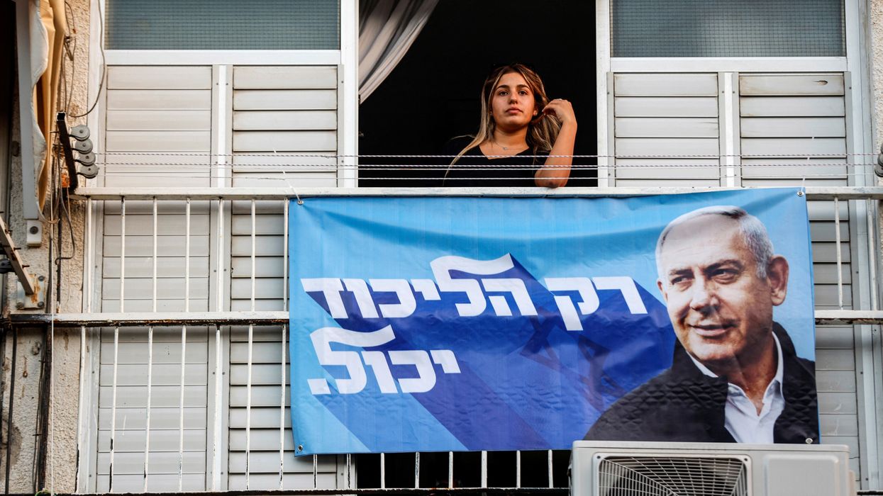 A woman looks out of a window displaying a campaign banner of Former Israeli Prime Minister Benjamin Netanyahu in Ramla, Israel.