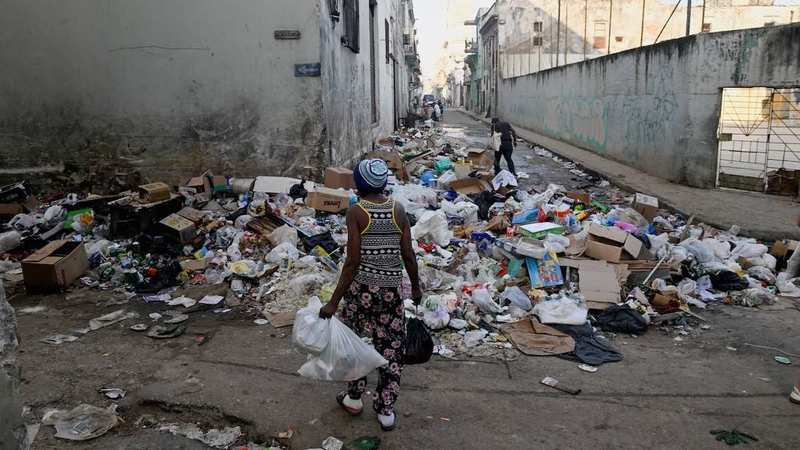 A residential street in Cuba with uncollected garbage bags piled up