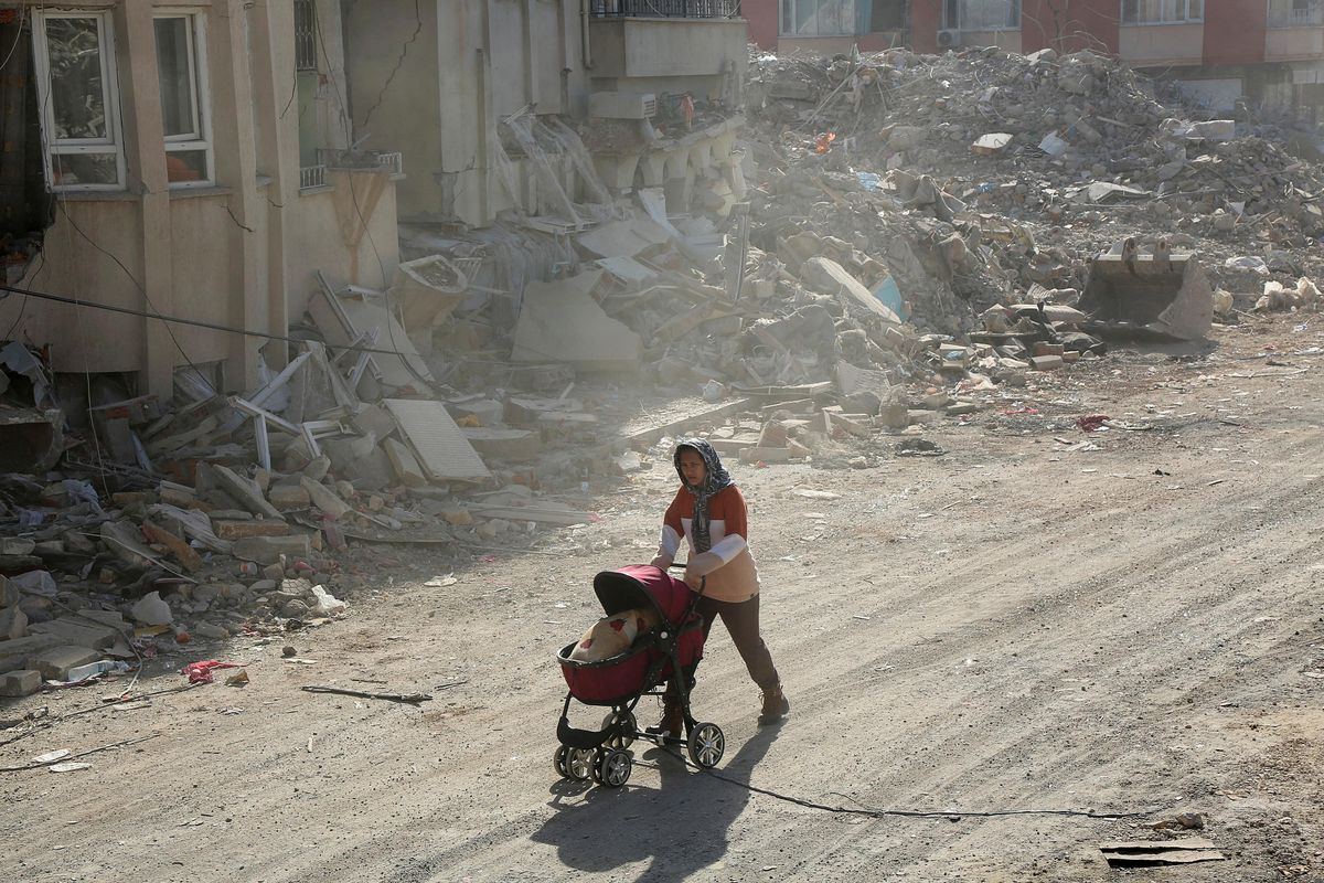 A woman pushes a baby carriage carrying her belongings, in the aftermath of the deadly earthquake, in Adiyaman, Turkey.