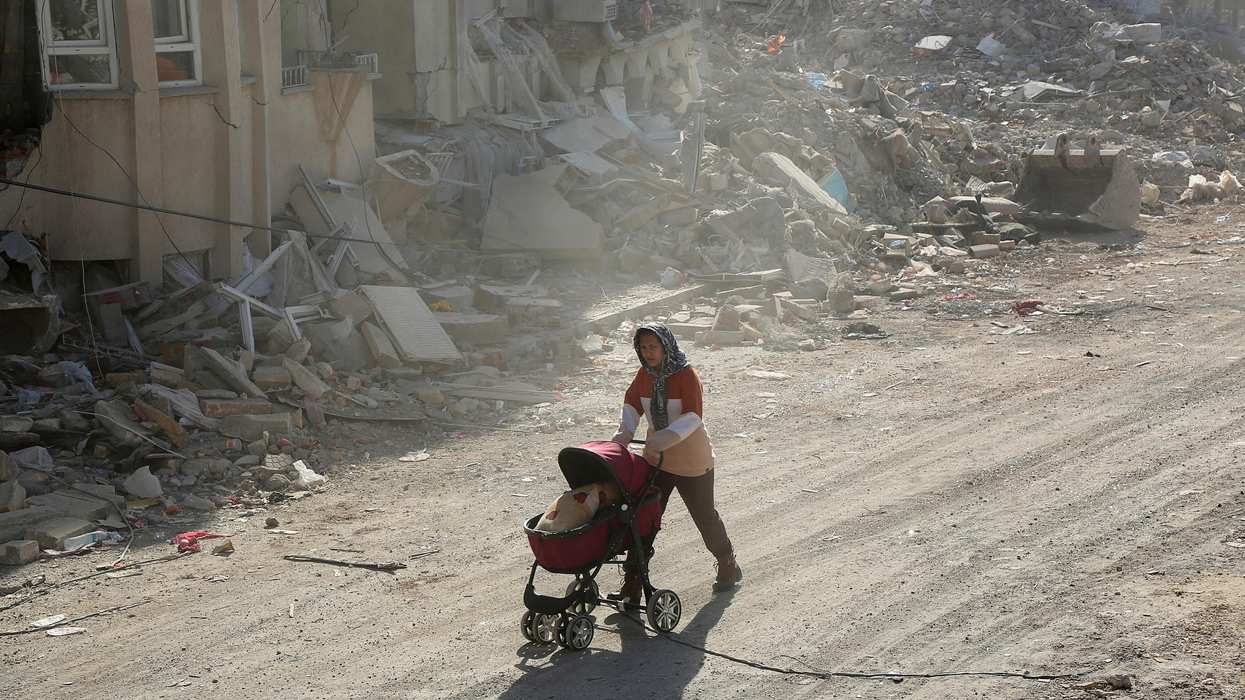 A woman pushes a baby carriage carrying her belongings, in the aftermath of the deadly earthquake, in Adiyaman, Turkey.