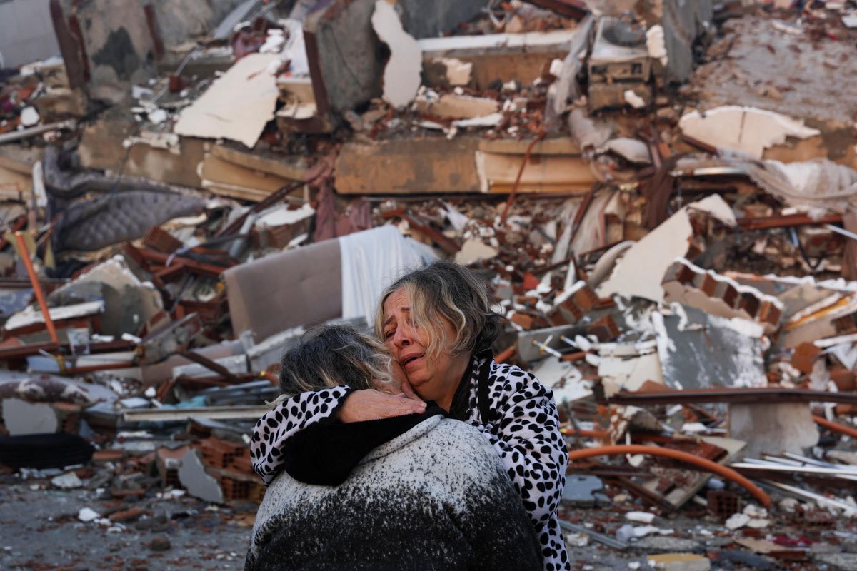 A woman reacts while embracing another person, near rubble following an earthquake in Hatay, Turkey. 
