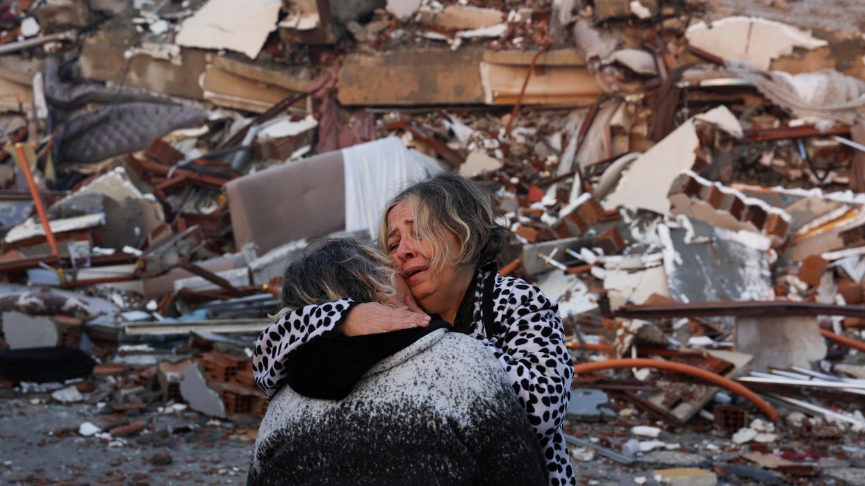A woman reacts while embracing another person, near rubble following an earthquake in Hatay, Turkey.