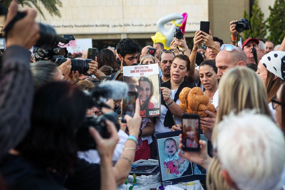 A woman shows a sign while people gather as they await news of hostages expected to be released by Hamas, amid a hostages-prisoners swap deal between Hamas and Israel, in Tel Aviv, Israel, November 24, 2023.