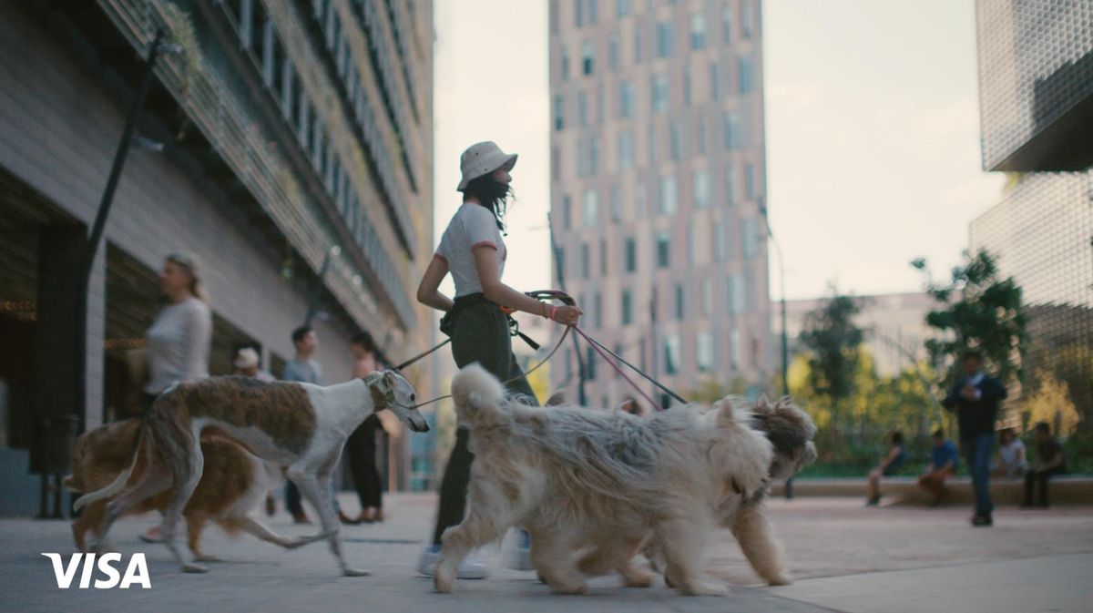 A woman walking several dogs through a plaza