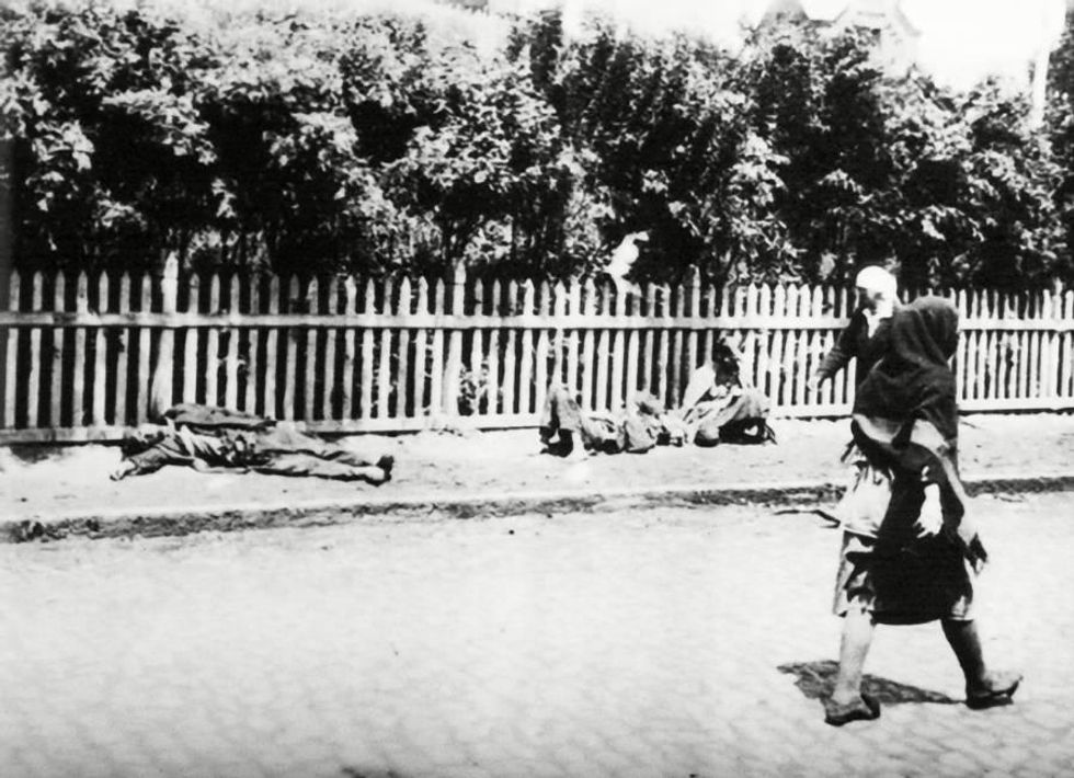A woman walks by two starving peasants dying on the streets of Kharkiv, Ukraine in 1932