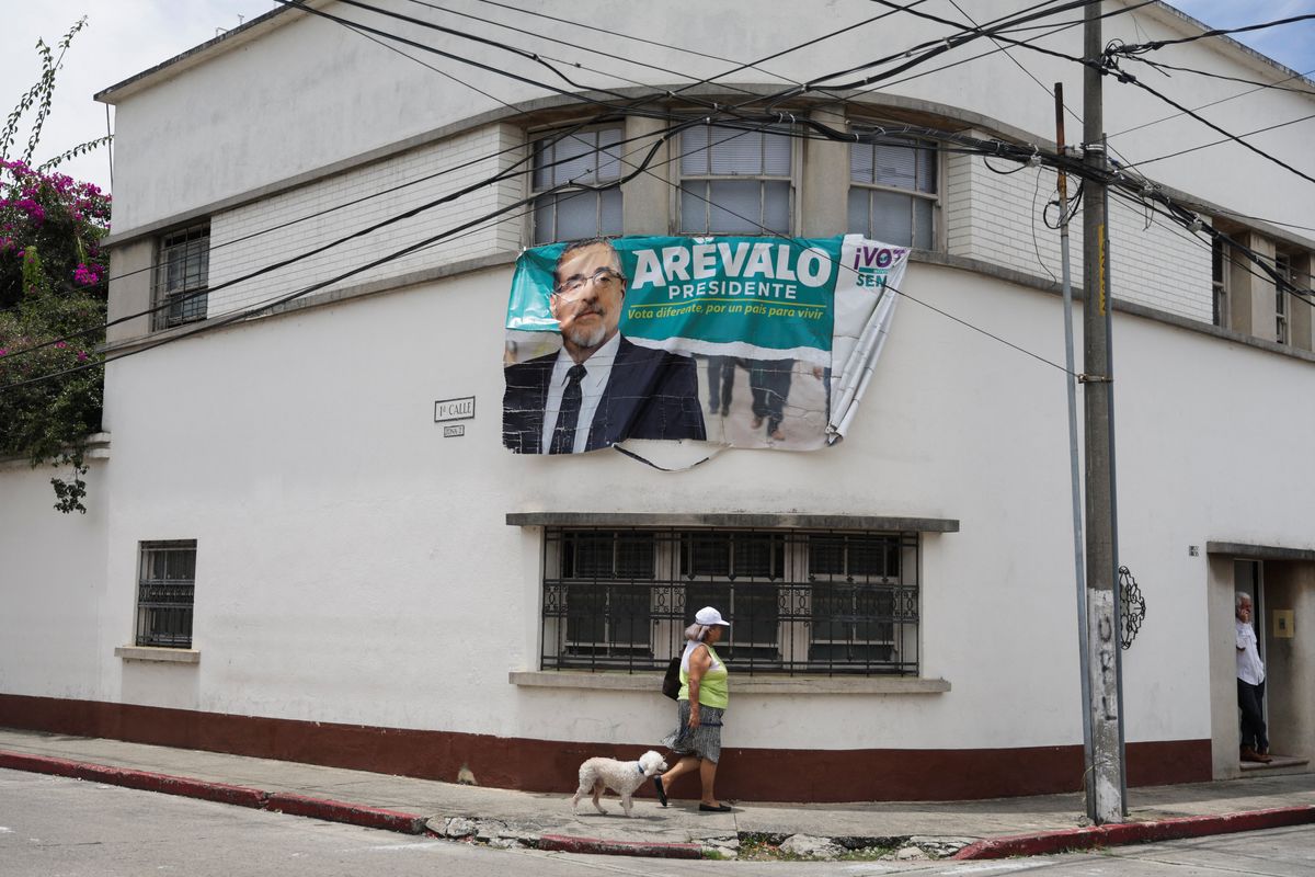 A woman walks next to a campaign sign of Guatemala's President-elect Bernardo Arevalo. 