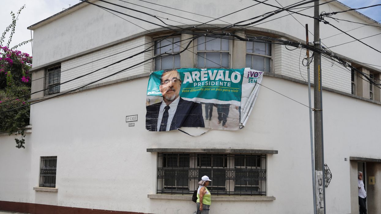 A woman walks next to a campaign sign of Guatemala's President-elect Bernardo Arevalo.