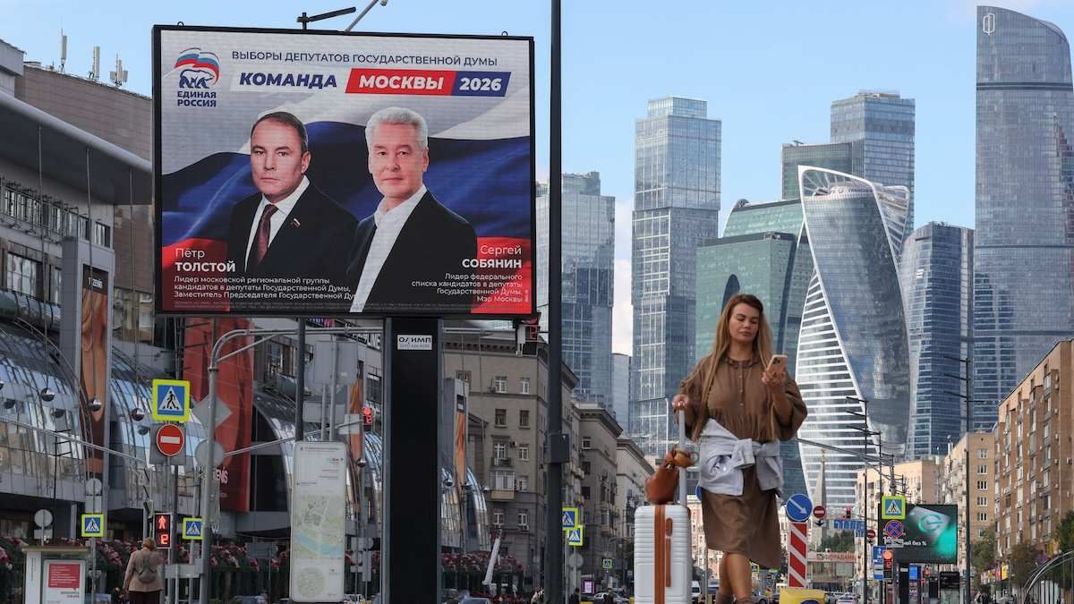 A woman walks past a billboard, displaying portraits of Moscow Mayor Sergei Sobyanin and Deputy Chairman of the State Duma Pyotr Tolstoy and promoting the United Russia party ahead of the upcoming parliamentary election, near the Moscow International Business Centre in Moscow, Russia.