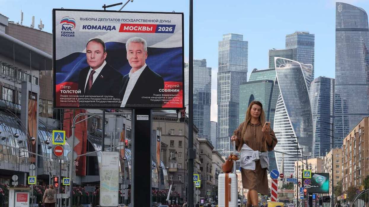 A woman walks past a billboard, displaying portraits of Moscow Mayor Sergei Sobyanin and Deputy Chairman of the State Duma Pyotr Tolstoy and promoting the United Russia party ahead of the upcoming parliamentary election, near the Moscow International Business Centre in Moscow, Russia.