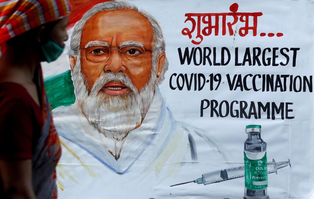 A woman walks past a painting of Indian Prime Minister Narendra Modi a day before the inauguration of the COVID-19 vaccination drive on a street in Mumbai, India, January 15, 2021.