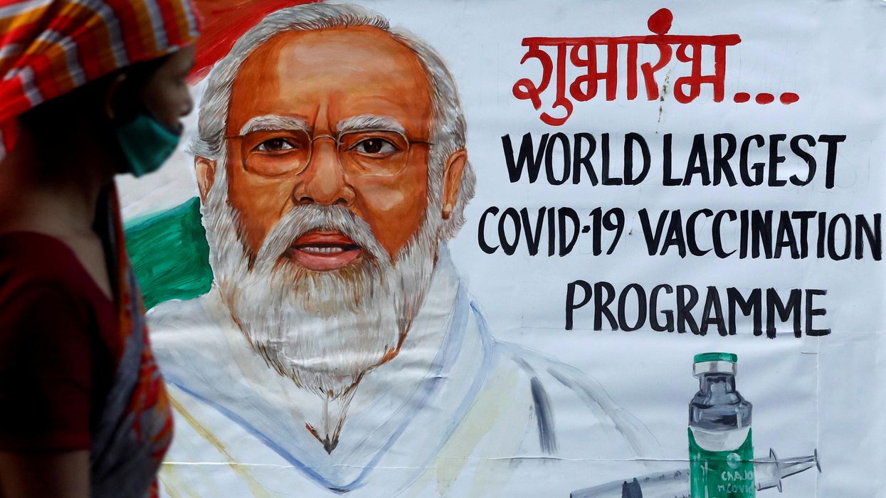 A woman walks past a painting of Indian Prime Minister Narendra Modi a day before the inauguration of the COVID-19 vaccination drive on a street in Mumbai, India, January 15, 2021.