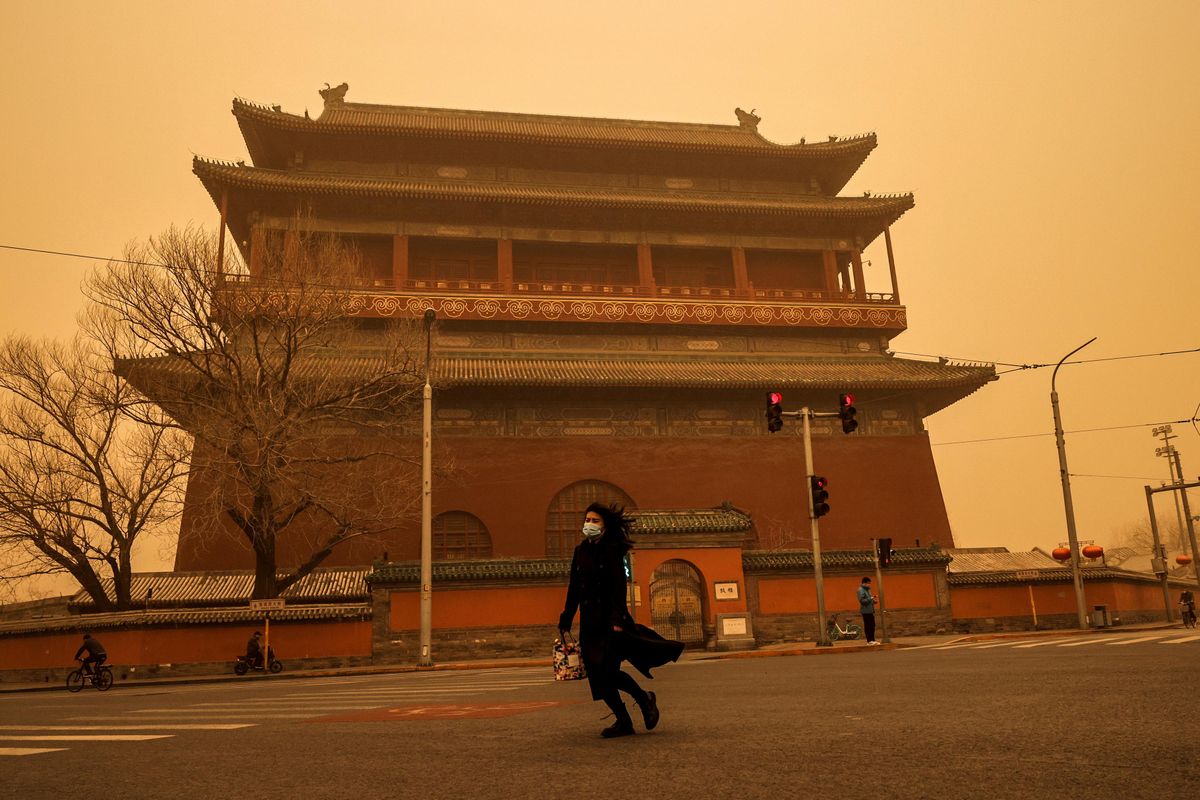 A woman walks past Drum Tower during morning rush hour as Beijing, China, is hit by a sandstorm, March 15, 2021.