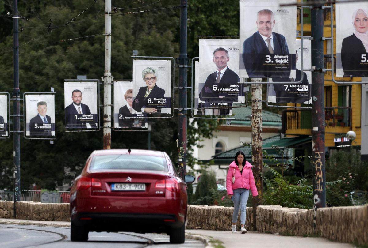 A woman walks past election posters in Sarajevo.