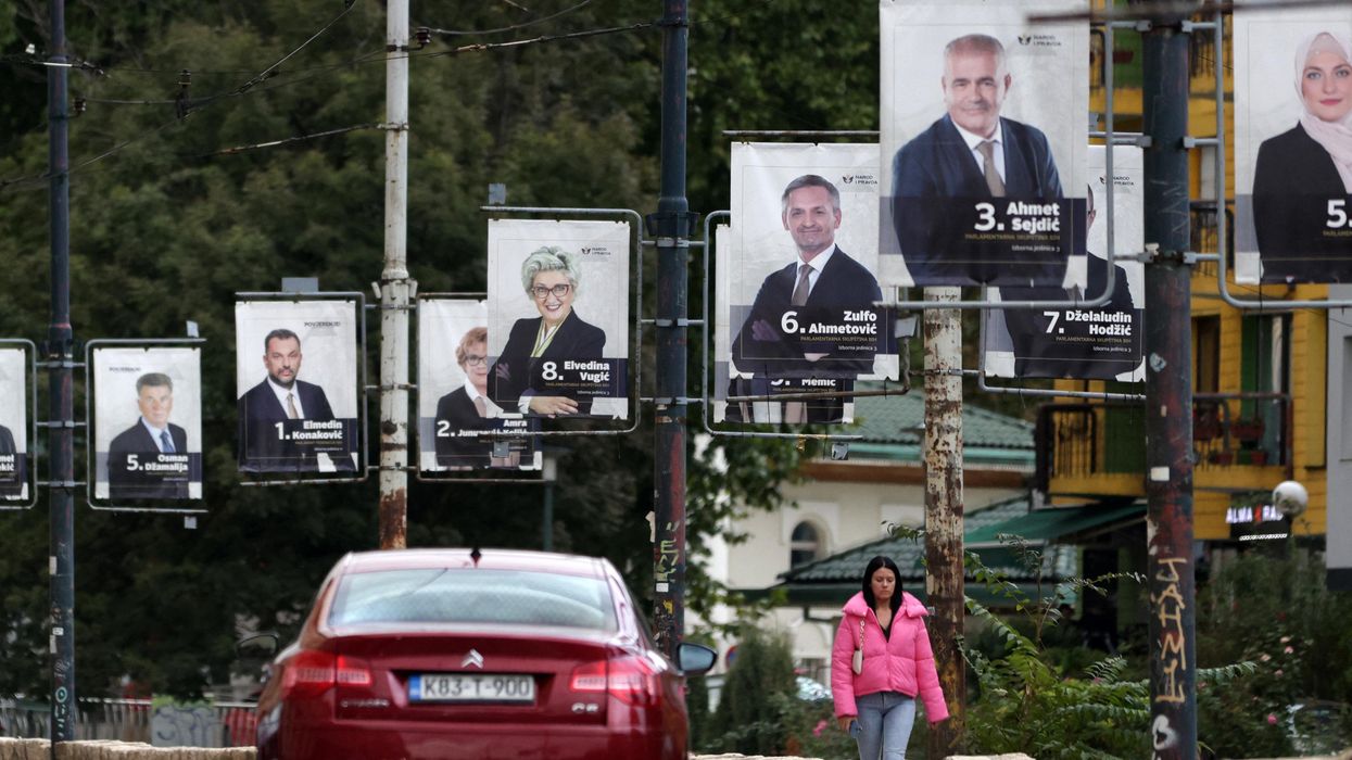 A woman walks past election posters in Sarajevo.