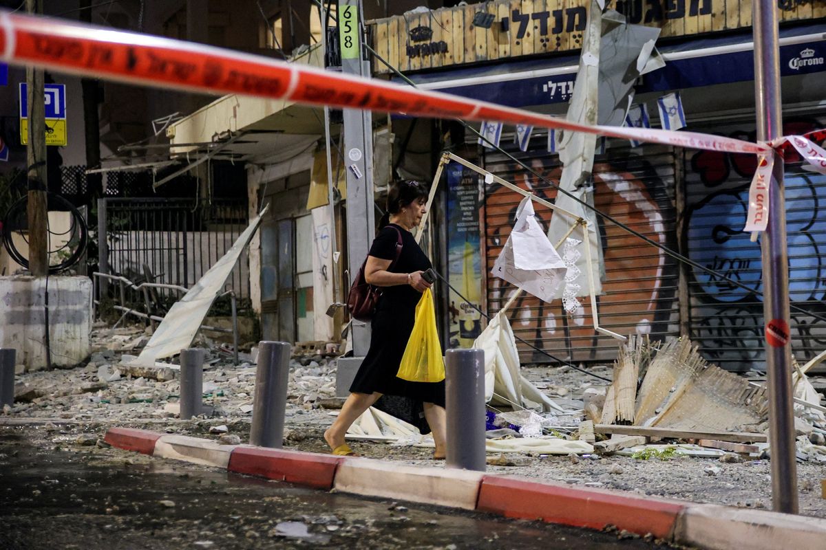 ​A woman walks past the site where a rocket launched from the Gaza Strip landed in Tel Aviv, Israel, on Oct. 7, 2023. 