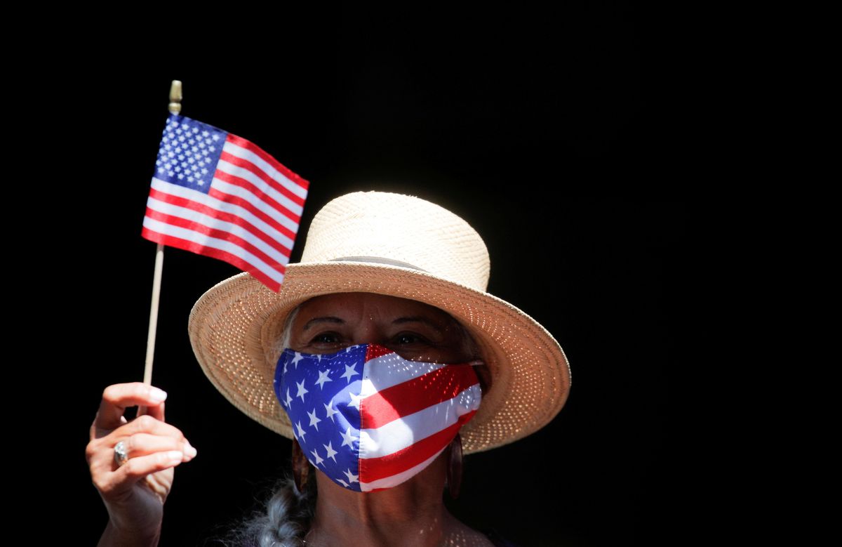 A woman waves a small U.S. flag as she takes part in the Hometown Heroes ticker tape parade, to honor essential workers for their work during the outbreak of the coronavirus disease (COVID-19), up New York City's "Canyon of Heroes" in lower Manhattan in New York City, New York, U.S., July 7, 2021