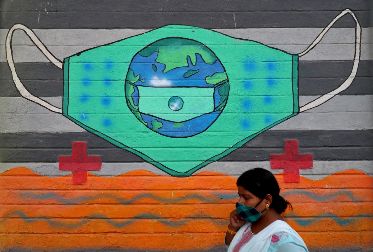 A woman wearing a protective face mask walks past a graffiti on a wall, amidst the spread of the coronavirus disease (COVID-19), in Mumbai, India, March 25, 2021.