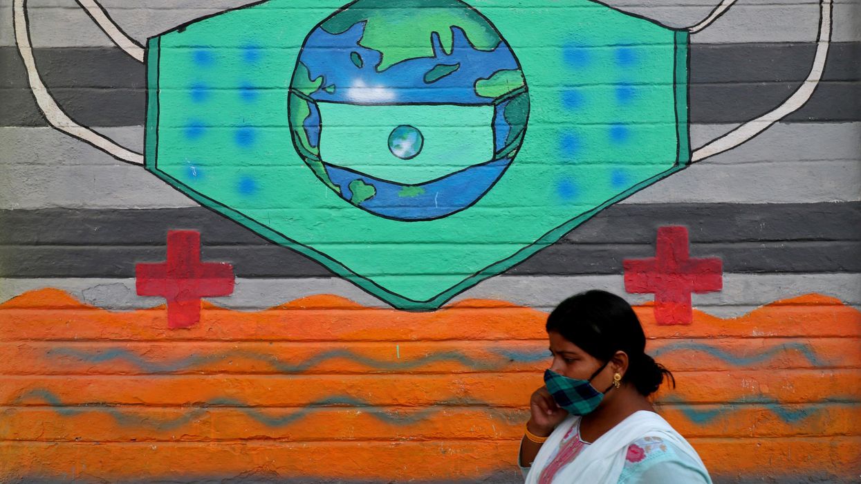 A woman wearing a protective face mask walks past a graffiti on a wall, amidst the spread of the coronavirus disease (COVID-19), in Mumbai, India, March 25, 2021.